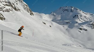 4K skiing footage, one woman skilled skier skiing on ski slope in long turns carving on sunny winter vacation day during ski holidays with clear blue sky high up in european alps mountains