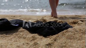 Slender young woman takes off her bikini and goes to swim in the sea