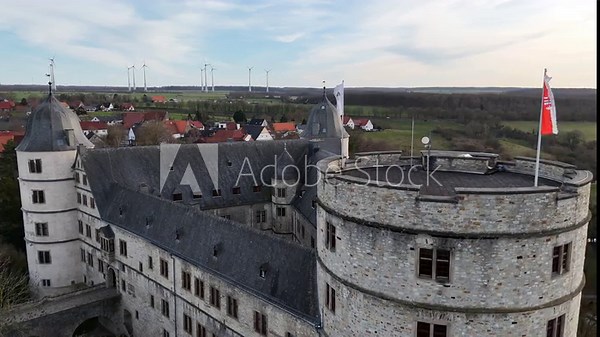 Static drone shot near the tower captures waving flags from a close side perspective against the sky.
