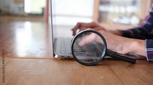 Woman with magnifying glass explores a laptop with a magnifying glass. Concept of searching the internet and computer websites. Travel, finances, discover and information. Use internet search concept.