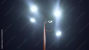 A modern street lamp shines brightly on a city street at night.