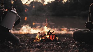 People pouring a warm drink around a campfire - Free Stock Video