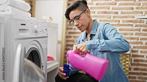 Young beautiful hispanic woman washing clothes pouring detergent at laundry room