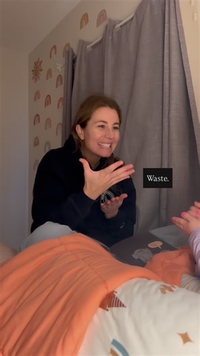 Christina_Pax on Instagram: "Crying, bye  VD: Mom is sitting on a pink blanket signing in American Sign Language to her young daughter (off camera). Mom is wearing a black hoodie and blue pants. Her brown hair in pulled back into a ponytail. The wall behind her has rainbow wallpaper and grey curtains. There is a Piggie & Elephant children’s book in front of her on the bed."