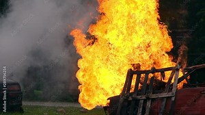 HD Slow motion wide shot of burning cars after an explosion in car accident. Billowing flames engulfing a car with smoke.