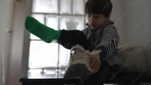 Footwear Frustration Little Boy Resisting Socks and Shoes by Doorway. Child irritated while trying to clothe himself, getting ready to go out