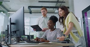 Camera view of two multi-ethnic managers helping their coworker complete work task on computer. Serious woman sitting at desk and entering information in technology device. Teamworking concept. Stock Video