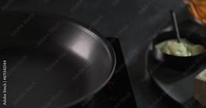 Woman pouring oil into a pan next to ingredients for spring rolls