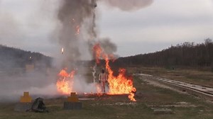 Stunt girl in a fiery explosion. Slow motion. Beautiful girl stunt runs across the field through the explosions and fire.