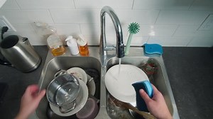Man washing dishes in the kitchen, top view. Caucasian man washing dishes in the kitchen after cooking and eating to happy family to eat slow motion video