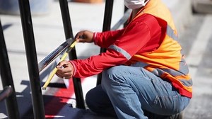 man measuring a grid with measuring tape, wearing mask and work vest - do it yourself