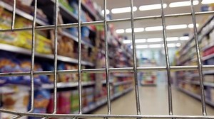 Supermarket shelves from inside a shopping basket. Aisle in a supermarket with the camera inside a wire basket.