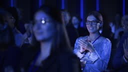 Beautiful Female Sitting in a Dark Crowded Auditorium at a...