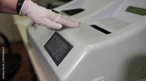 Female lab technician sets up a laboratory machine for blood analysis. Modern medical technology.