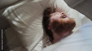 High angle time lapse of male patient with mental disorder lying on bed in ward having seizure, shaking his head and screaming