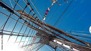 Sun flair shines through tall ship sailboat ropes and rigging. DUTCH ANGLE