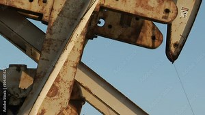 An oil derrick pumping oil passes before the sun. Stock Video