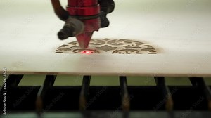 A machine for laser cutting of sheet wood. A modern CNC laser cutting machine cuts sheet wood into shapes. During the cutting process, bright burning sparks fly out of the laser beam.
