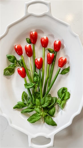 Janine Graff on Instagram: "Tomato Tulip Caprese Bouquet 🌷Celebrate Valentine’s Day and welcome spring with a stunning and delicious Caprese bouquet! Perfect for impressing your loved ones! This delightful dish not only tastes amazing but also serves as a vibrant centerpiece. Here’s how to craft it using simple ingredients and skewers: - Cherry tomatoes - Mini mozzarella - Fresh basil - Green onions (cut to fit the skewer) - A sprinkle of salt - A drizzle of olive oil - A splash of balsamic Dir