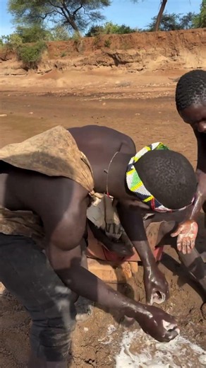 Hadzabe tribe bushmen help each other to keep clean in the bush