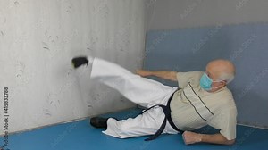 Sportsman with black belt and medical mask training leg exercise