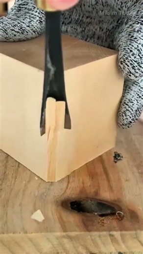 carving and shaping the corner of a solid wooden block using a sharp metal wood chisel manual tool