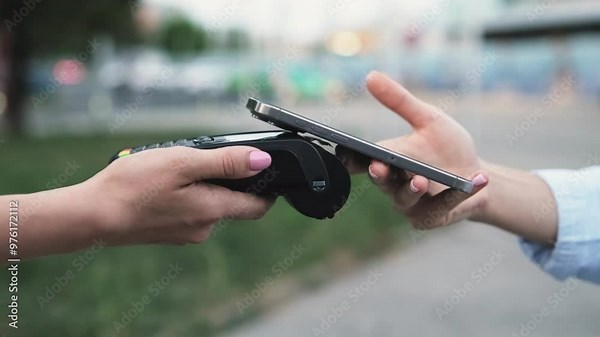 Woman uses smartphone to pay for purchase vie POS terminal on city street closeup. Online banking service for small business conveniences