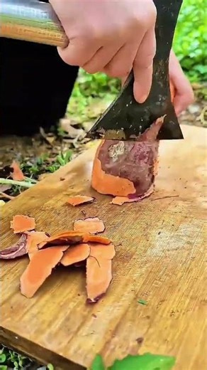 peeling the sweet potato skin using a sharp small axe and putting it on the wood board