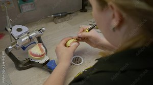 Artificial Denture production at the modern stomatology laboratory. Using small stomatology tools for production of denture replacements. Producing denture treatments using stomatology instruments.