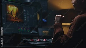 Female video maker works in studio on computer, uses color grading control panel. The colorist edits video, makes color correction for movie. Program interface with film footage, RGB wheels and levels