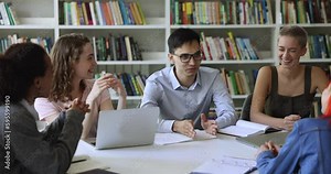 Happy team of students studying together, sit at table, preparing for exam in library, laughing at funny joke, talking, having fun, doing research project homework, creative assignment, get knowledge