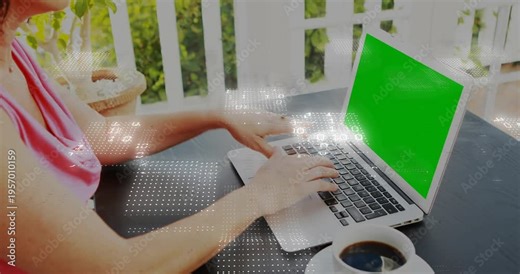 Mature woman typing on porch laptop, causing binary overlay over keys and green screen for work