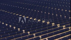 Smooth aerial shot over a solar panel field, capturing the large array of panels generating renewable energy