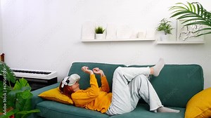 woman laying on sofa relaxing and playing VR and using futuristic artificial intelligence at home.. the concept of metaverse, virtual reality, future, technology, and internet of things.