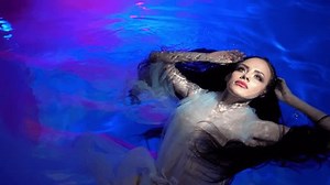 Slow Motion Woman in a white dress is dancing underwater while showing a show.
