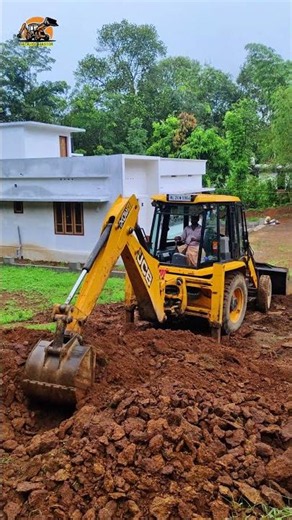 Red, thick soil is being rammed and leveled using a JCB. |BackhoeMaster|