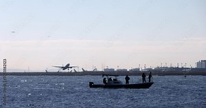 海辺の飛行場から離陸する飛行機と釣り船が見える風景。