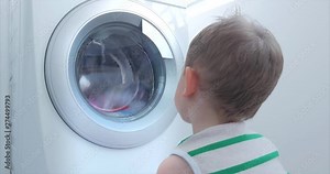 Cute Child Looks Inside the Washing Machine. Cylinder Spinning Machine. Concept Laundry Washing Machine, Industry Laundry Service.