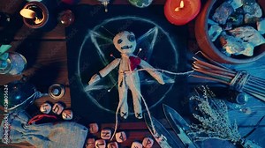 Creepy voodoo doll on dark scary spiritual wizardry table with candles and magic attributes for halloween sorcery and curse.