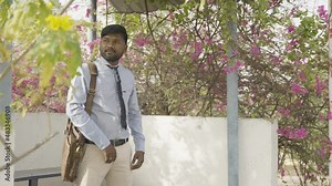 young man waiting for public transportation at bus stop while going office - concept of transportation, commutation and daily lifestyle