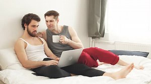 Happy Gay Couple Using Tablet in Bed. Gay Couple