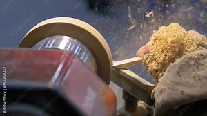Carpentry, craftsmanship, design, manufacturing concept. Close up side view - professional man carpenter using skew chisel for shaping piece of wood on wood turning lathe at workshop - slow motion