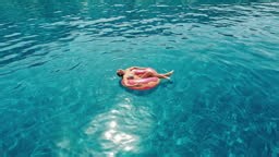 Woman sunbathing on a swimming float. Enjoying the hot summer sun and...