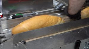 Fresh Bread Packaging Line in Bread Factory. Fresh Bread Wrapped in Clear Packaging Film at Packaging Line. Production Line Worker Works at the Bread Factory.