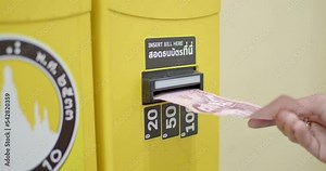 A 100 baht banknote is inserted into a coin changer, changing from banknotes to coins.