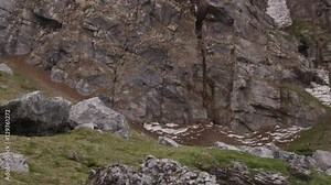 Slow motion tilt up - bird cliff with kittiwakes slowly circling overhead in snow