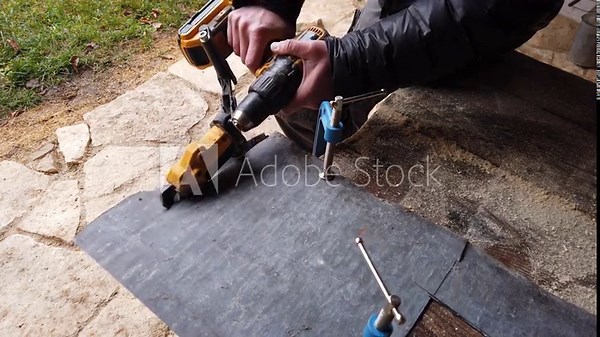 Hands of a tinsmith working with cordless shear accessory for cutting sheet metal mounted on screw diver