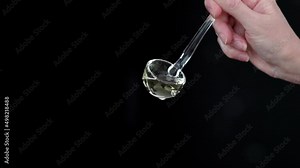 Pouring cooking oil with a glass ladle in slow motion against a black background 100 fps