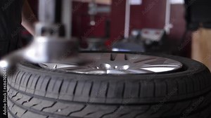 Repairman clamp wheel disk in fitting machine to remove rubber tire.