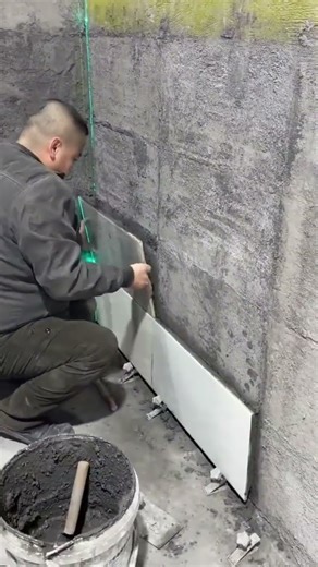 the process of installing rectangular white ceramic tiles on the walls of a house #construction